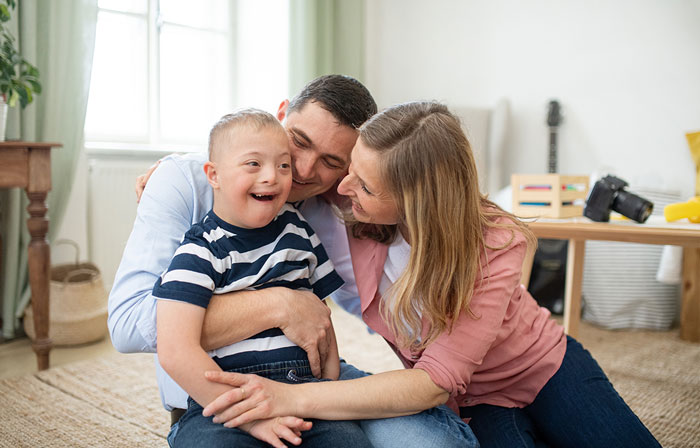 A man and woman sit on the floor, sharing a playful moment with a child